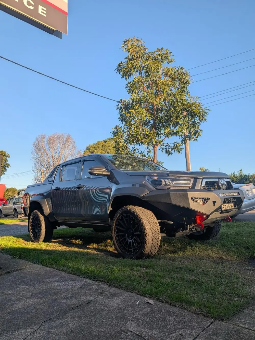 A blacked-out Toyota Hilux with a bull bar and lift kit outside the Apex Auto Air workshop in Lambton, Newcastle